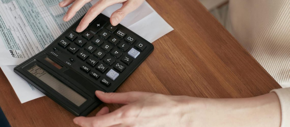 Close-up of a woman using a calculator and reviewing bills at home.